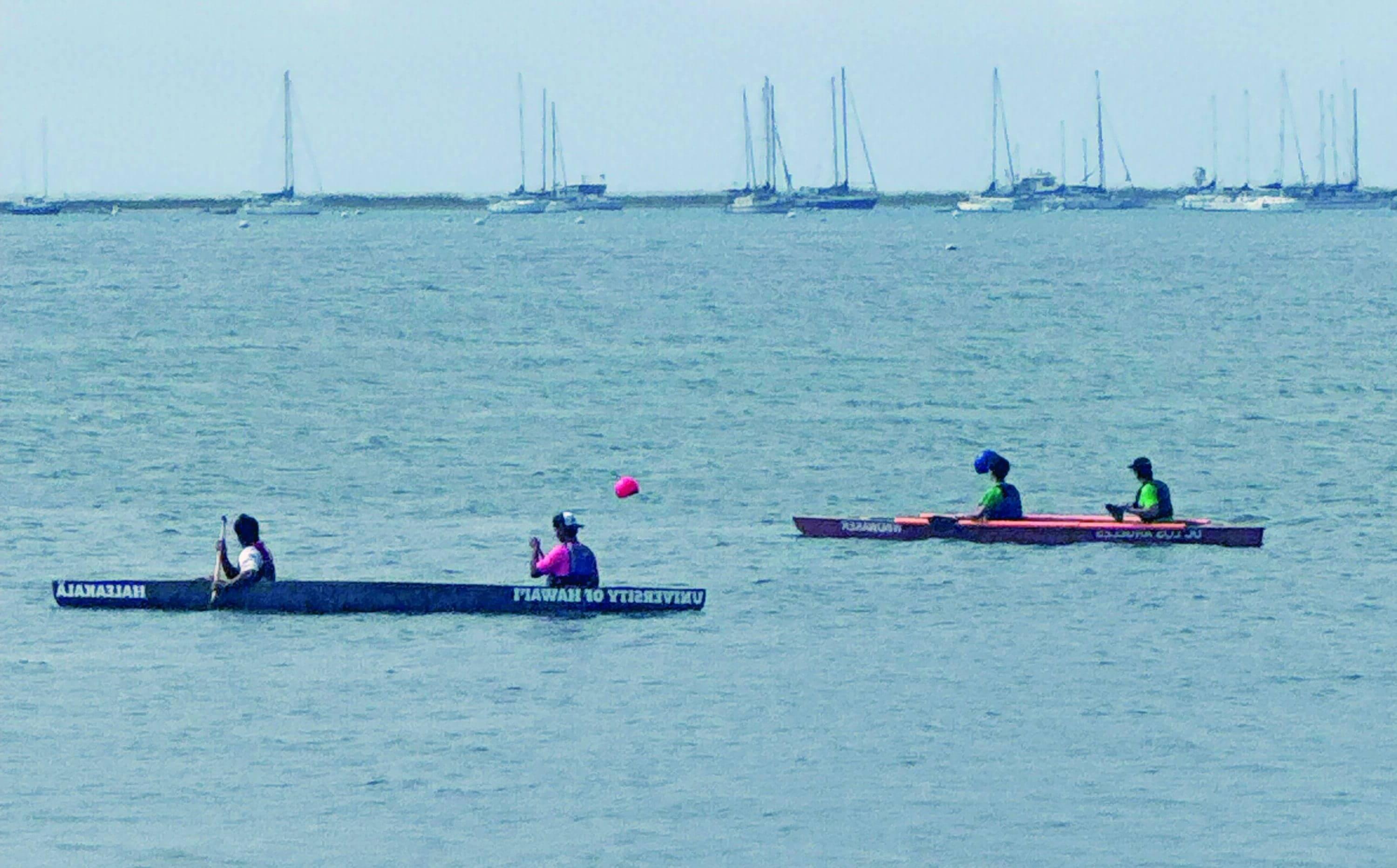 Two-person cement canoes are put to task in the bay with sail boats in the background.